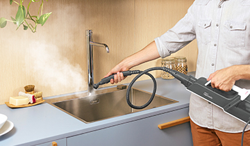 L'immagine mostra la pulizia a vapore del lavello della cucina con lo spazzolino tondo piccolo con setole in nylon