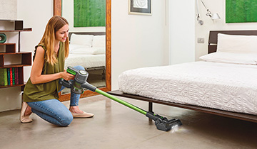 The image shows a girls who vacuums under the bed with Polti Forzaspira D-Power SR500