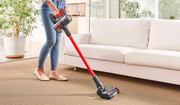 The image shows a girs who vacuums a carpet with Polti Forzaspira D-Power SR550