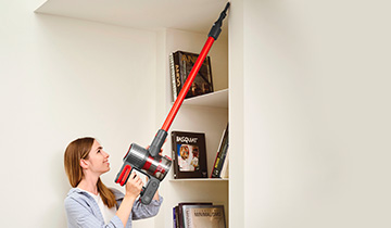 The image shows a girs who vacuums high places with Polti Forzaspira D-Power SR550