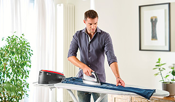 The image shows a man who is ironing jeans