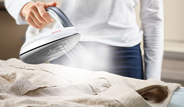 La imagen muestra a una chica planchando una camisa, utilizando la funcion Steam Pulse del Polti Vaporella Next VN18.45